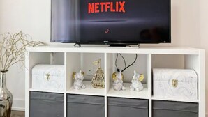 Een televisie op een witte standaard, met het Netflix-logo op het scherm.