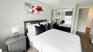 Een moderne slaapkamer met een groot bed, een nachtkastje en een spiegel.