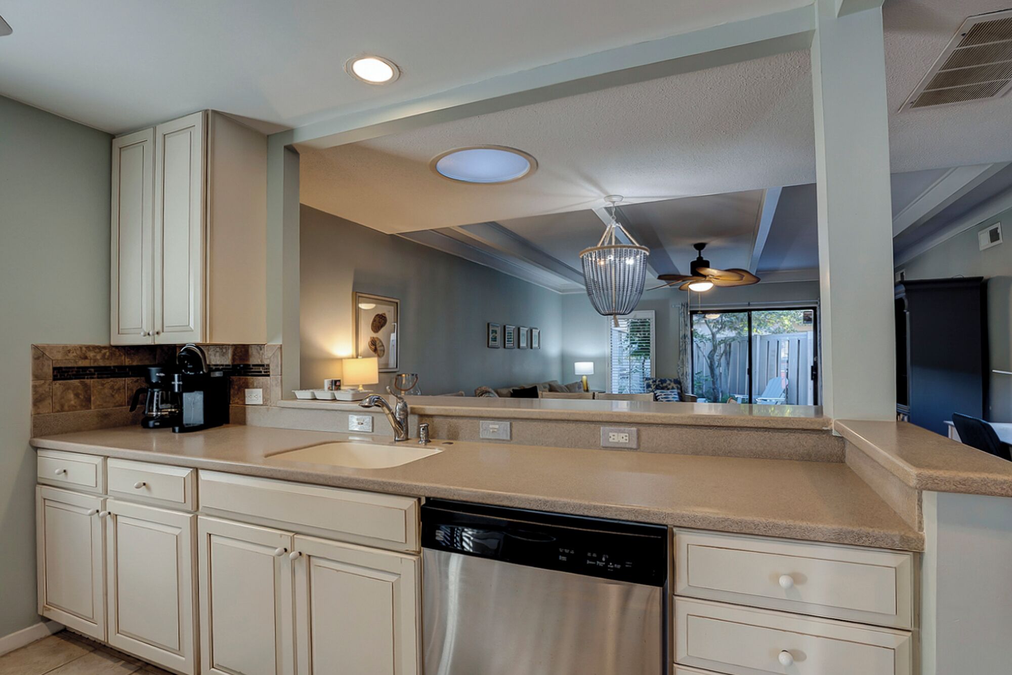 A modern kitchen with a dishwasher, double sink, and a large mirror.