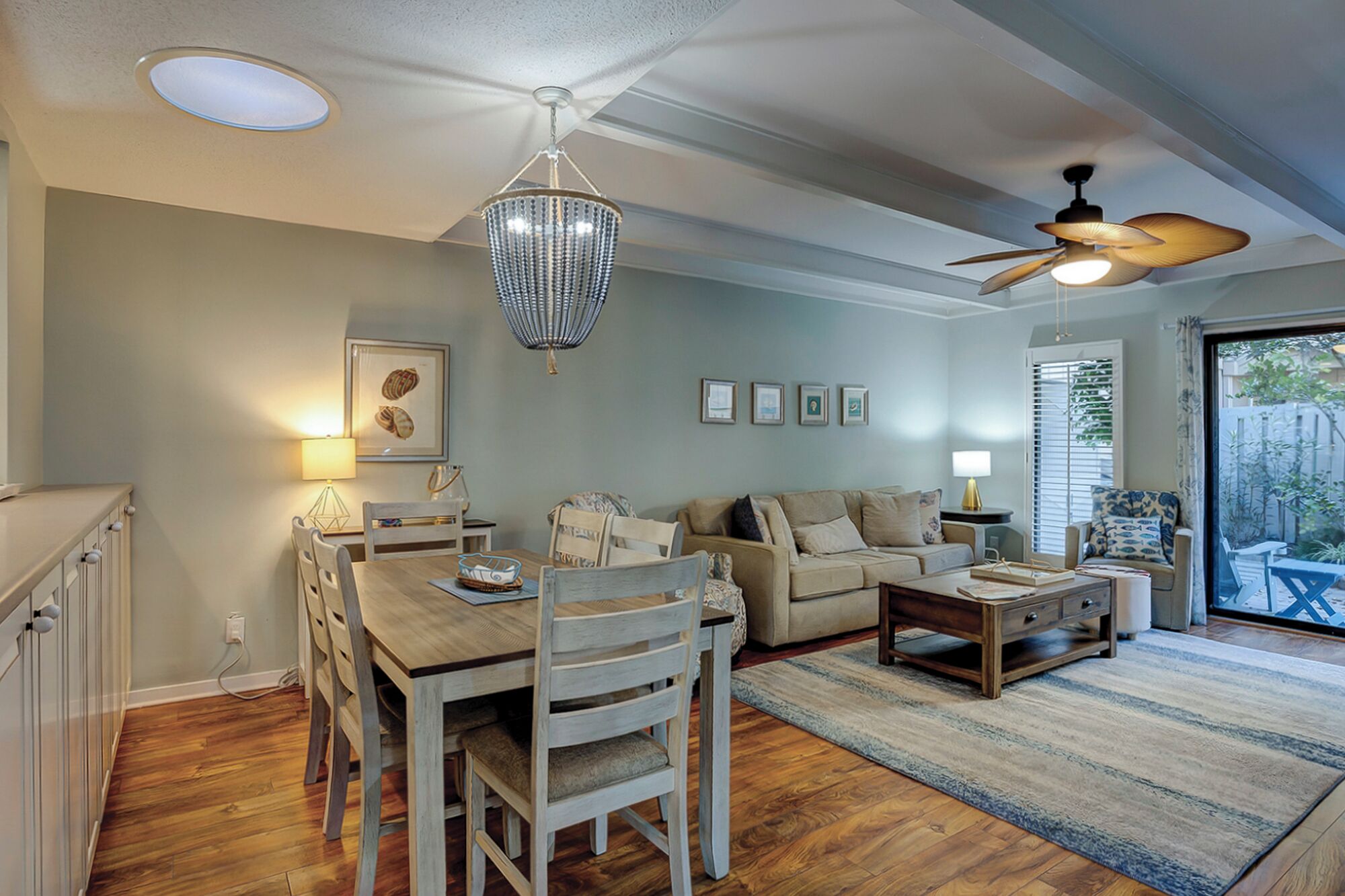 A spacious living room with a dining area, a ceiling fan, and a view of the outdoors.