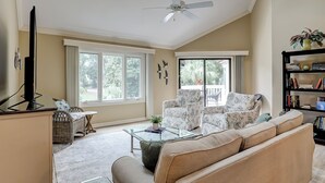 A living room with a sofa, armchairs, a coffee table, a TV, and a bookshelf. - Sunset Rentals | Colonnade Club 150 (Hilton Head Island)