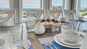 Une table à manger dressée avec de l’assiette blanche, des bols et des verres, un pichet et un panier de biscuits.