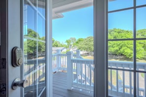A view from a room with a glass door leading to an outdoor deck with a white railing.