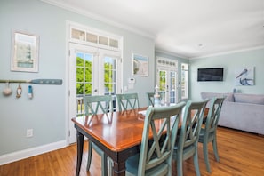 A dining area with a wooden table and chairs, a sofa, and artwork on the walls.