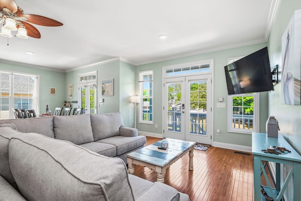 A living room with a sofa, coffee table, and a TV mounted on the wall.