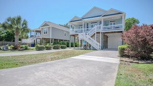 Een tweelaags huis met een veranda, een overdekte patio en een trap naar een balkon op de tweede verdieping.