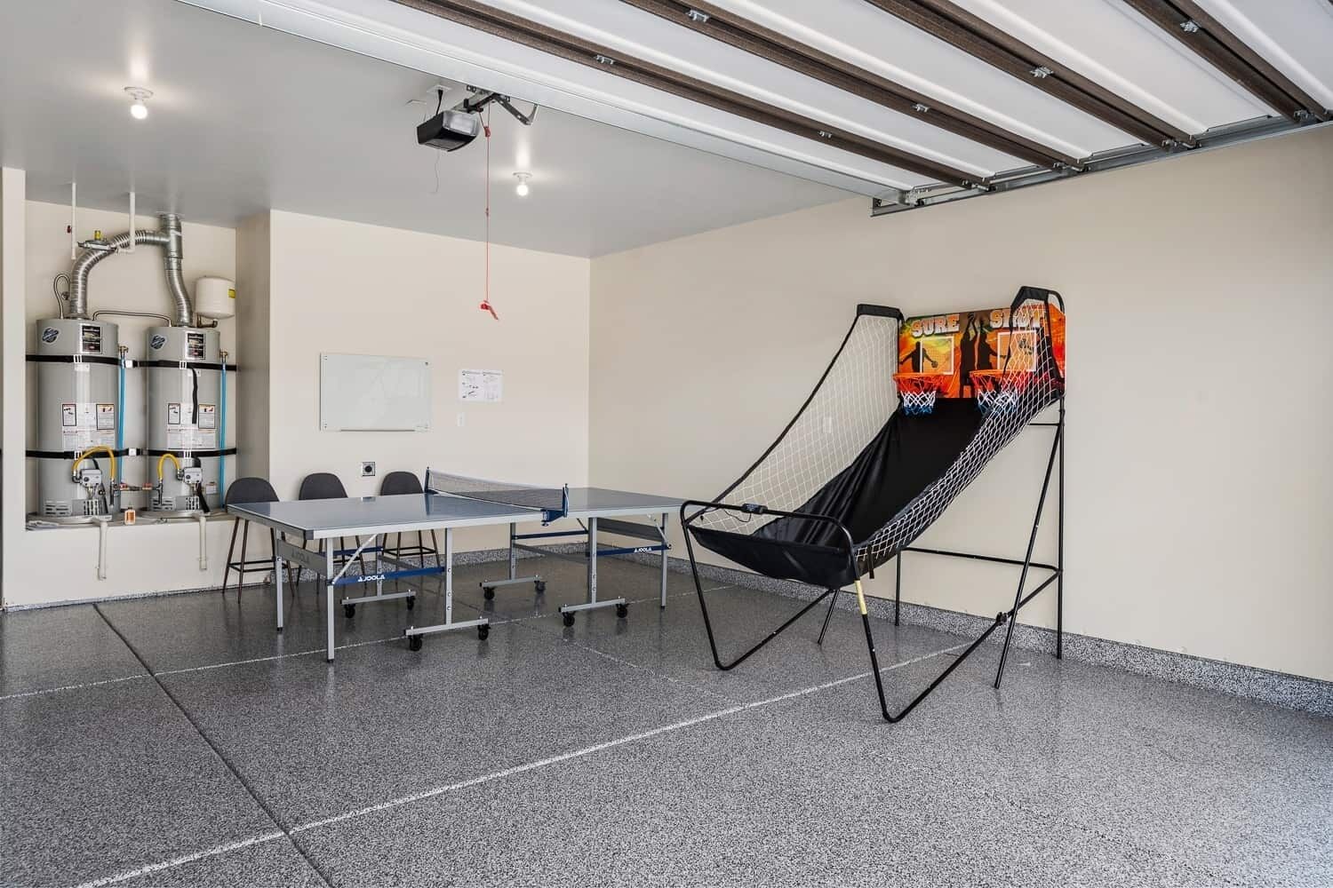 Una habitación con mesa de ping pong, sillas, proyector y un trampolín.