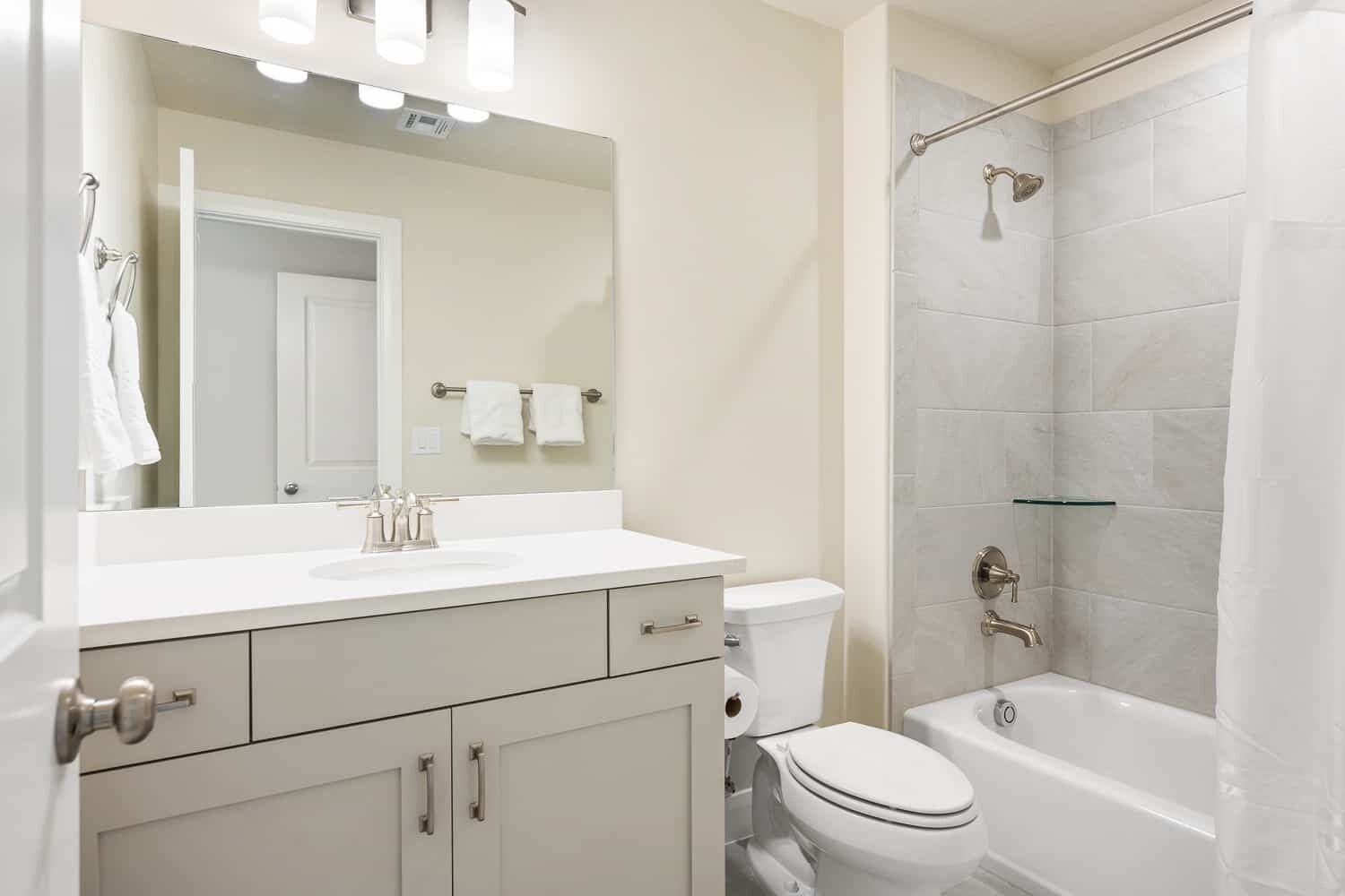 Une salle de bain avec un meuble-lavabo blanc, des toilettes, une douche dotée d’une étagère en verre et une baignoire.