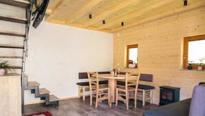 Un interior de madera con una mesa de comedor, sillas, un sofá, una chimenea y una escalera.