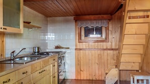 A kitchen with wooden cabinets, a stove, and a window with a lace curtain.