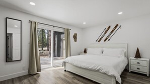 A bedroom with a large bed, a nightstand, a mirror, and a ski rack. - 793 McCoury | 4BR/3BA Incline Village | Mountain views, fireplace (Incline Village)