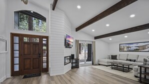 A spacious living area with a wooden floor, a large window, a fireplace, and a sofa. - 793 McCoury | 4BR/3BA Incline Village | Mountain views, fireplace (Incline Village)