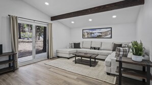 A modern living room with a sofa, coffee table, and a large window with curtains. - 793 McCoury | 4BR/3BA Incline Village | Mountain views, fireplace (Incline Village)