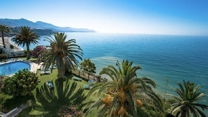 Une propriété située sur la côte, dotée d’une piscine, de palmiers et offrant une vue sur la mer et les montagnes.