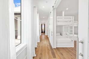 Una habitación de hotel moderna con literas, suelo de madera y paredes blancas.