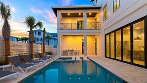 A modern two-story house with a swimming pool, lounge chairs, and a dining area. - Bullish on Beaches|Easy Beach Access|Stunning Views|New Construction (Inlet Beach)