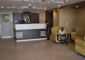 A reception area with a counter, two armchairs, and a ceiling fan. - Sharma Residency Madurai (Madurai)