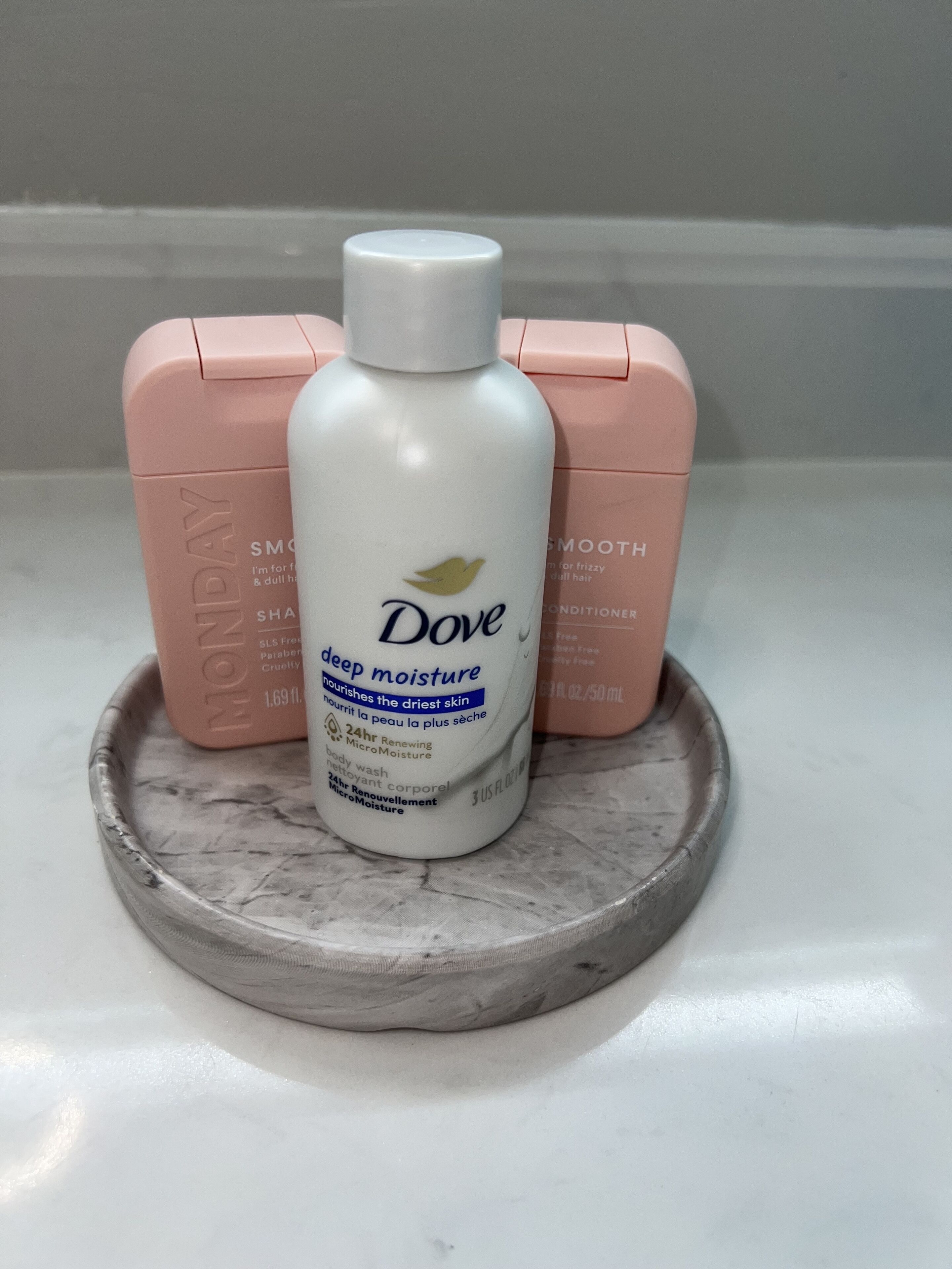 Dove deep moisture body wash on a marble tray with two pink boxes beside it.