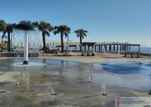 Ein Park am Wasser mit einem Brunnen, Palmen und einem Steg.