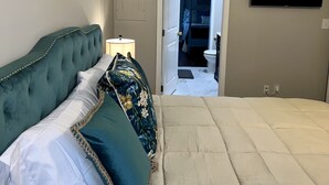 Ein Schlafzimmer mit einem Bett, einem Nachttisch, einem Gemälde und einem Fernseher.