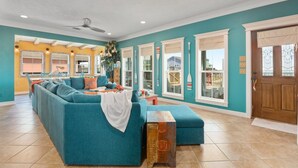 Un salon spacieux avec un canapé de couleur turquoise, une table basse en bois et un ventilateur de plafond.