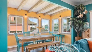 Un espace repas avec une table et des chaises en bois, de grandes fenêtres et une vue sur l’extérieur.
