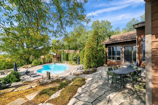 Ein Garten mit Pool, Terrassenmöbeln und einem Holzhaus.