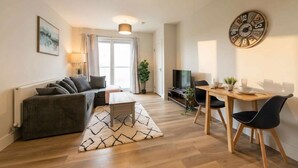 A modern living room with a sofa, coffee table, and dining area with chairs.