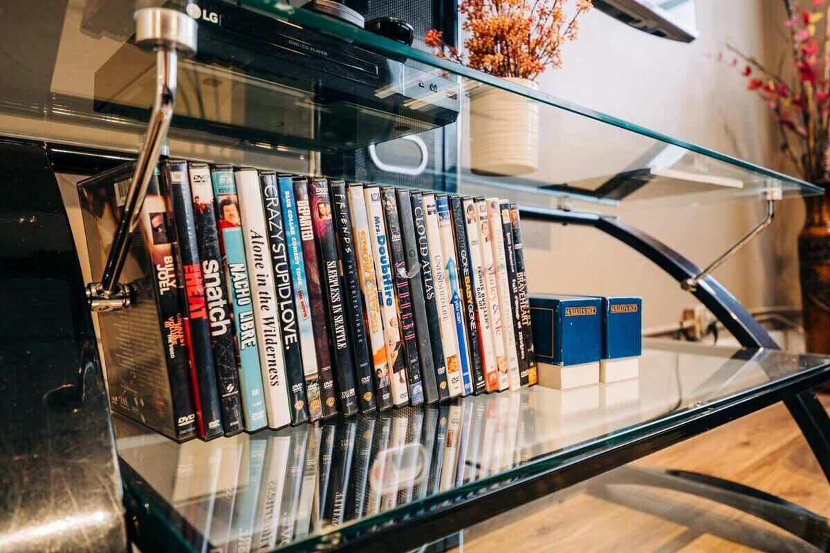 A glass shelf with a row of DVDs and two blue bookends.