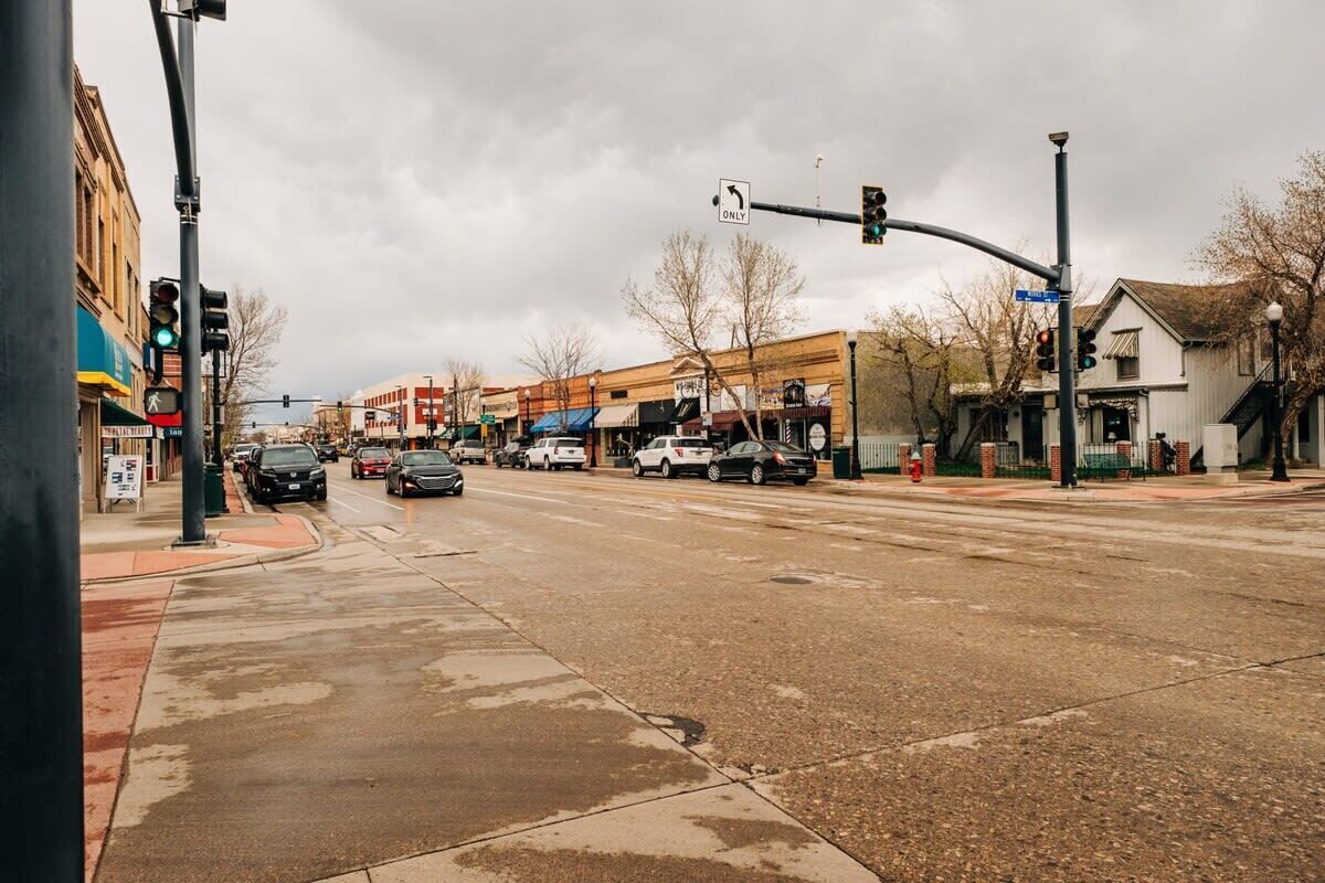 A street intersection with multiple lanes, traffic lights, and buildings.