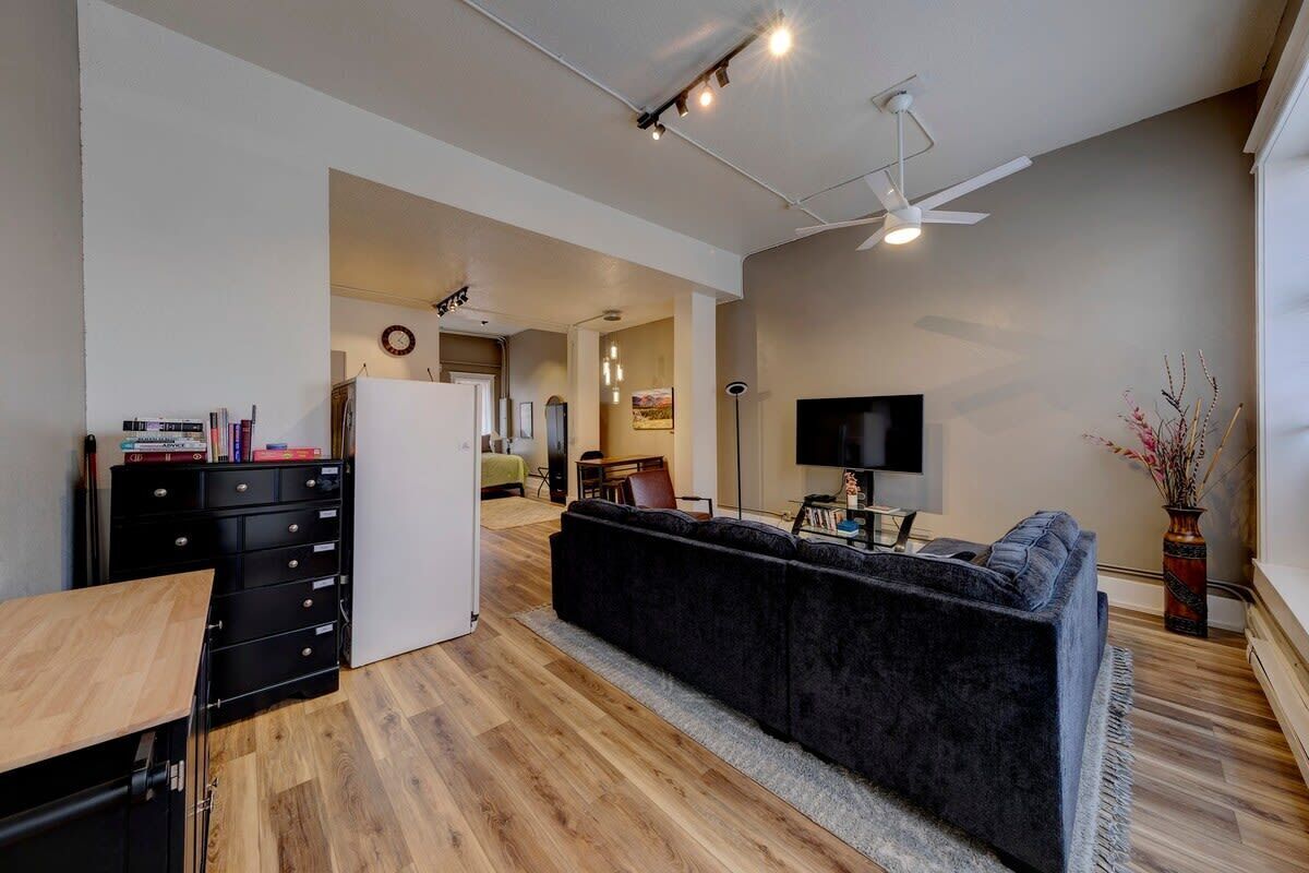Un salon moderne avec un canapé foncé, un téléviseur à écran plat et un plancher en bois.