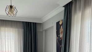 Habitación de hotel con dos camas, cabecera, un cuadro y una ventana con cortinas.