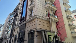 Un hotel de varios pisos con una llamativa fachada de vidrio azul, balcones y un asta de bandera.