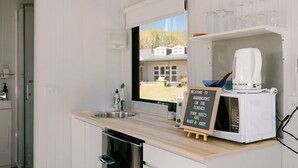 Eine Küche mit einer Kaffeemaschine, einem Kreidetafel-Schild und einem Fenster mit Blick auf ein Haus.