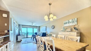 A spacious dining area with a wooden table and chairs, a chandelier, and a view of the outdoors.