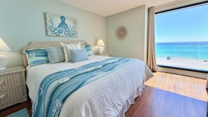 A bedroom with a large bed, a view of the beach, and a ceiling fan. - Gulfgate 403 - Beautiful Pet Friendly 2 Bed Condo (PANAMA CITY Beach)