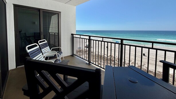 A balcony with a view of the beach, a table, and two chairs. - Gulfgate 409 - Pet Friendly Condo on the Beach! (PANAMA CITY Beach)
