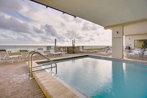 An indoor swimming pool with a view of the ocean, lounge chairs, and a 'NO DIVING' sign.