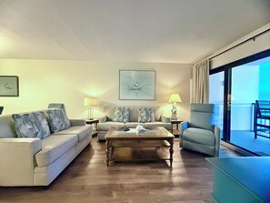 A living room with a sofa, armchairs, a coffee table, and a painting on the wall.