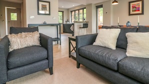A modern living room with grey sofas, a coffee table, and a kitchen in the background. - Court Lodge (Taunton)