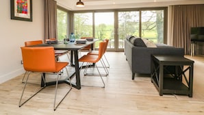 A modern living room with a dining area, large windows, and a TV. - Court Lodge (Taunton)