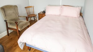 A bedroom with a single bed, a wooden chair, a nightstand, and a lamp. - Tí Coilín Mhac (Maumeen)