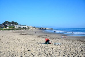 Une plage avec une chaise rouge et quelques personnes au loin.