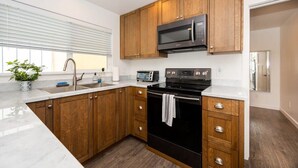 A modern kitchen with wooden cabinets, a black stove, a microwave, and a sink. - Harbor House A, overlooking Santa Cruz Harbor (Santa Cruz)