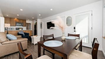 Una sala de estar moderna con una mesa de comedor, sofás y una cocina al fondo.