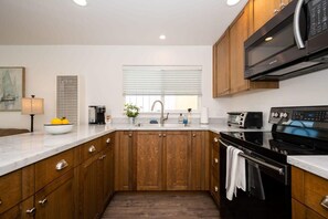 Une cuisine moderne avec des meubles en bois, un four à micro-ondes en acier inoxydable et un four encastré.