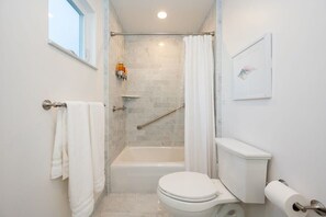 A bathroom with a bathtub, toilet, and shower curtain. - Harbor House A, overlooking Santa Cruz Harbor (Santa Cruz)