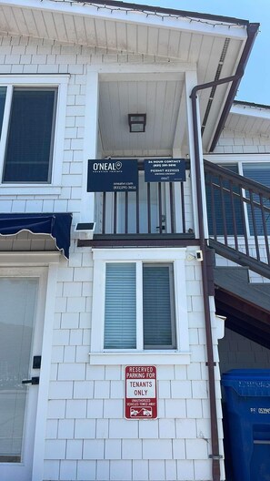 A building with a sign indicating O'Neal Vacation Rentals, a 24-hour contact number, and a reserved parking sign for tenants only.