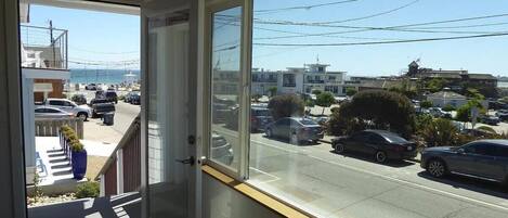 A view from a room with a large window overlooking a street with parked cars and buildings.