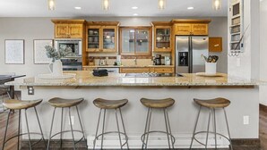 Een moderne keuken met houten kastjes, een granieten aanrecht en barstoelen.